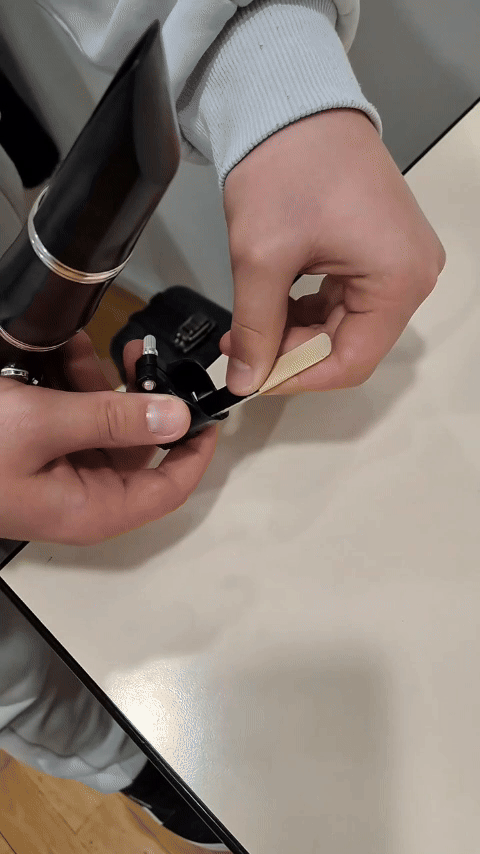 Hands attaching the best clarinet ligature for beginners from EASY LIG onto a clarinet mouthpiece